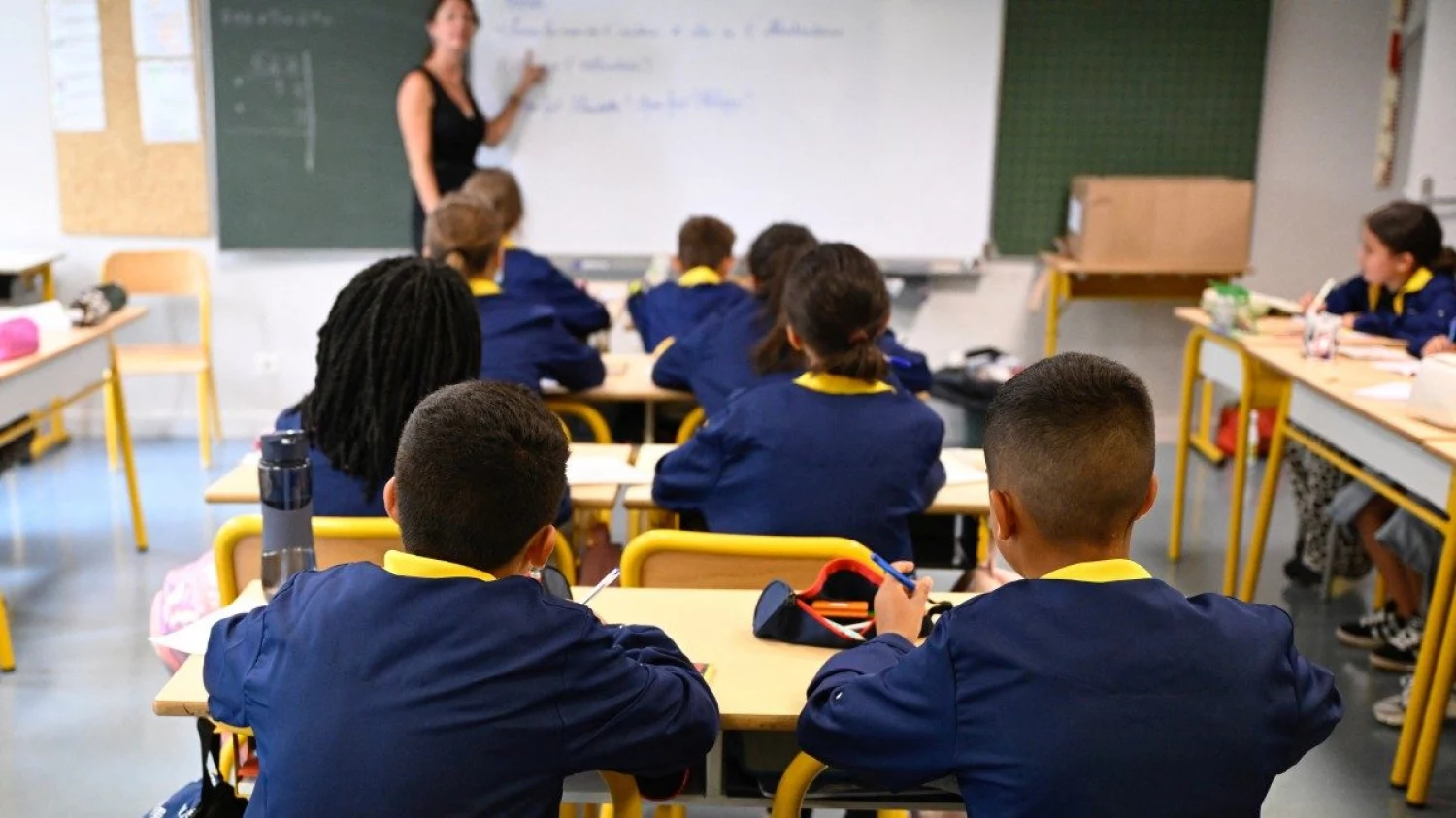 Des élèves de l'école primaire Les Bordes, portant leur uniforme unique, écoutent leur professeur lors de la rentrée scolaire, à Metz, dans le nord-est de la France, le 2 septembre 2024